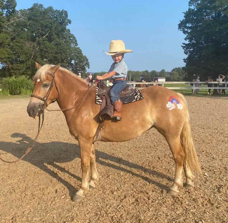Child in straw hat riding pony