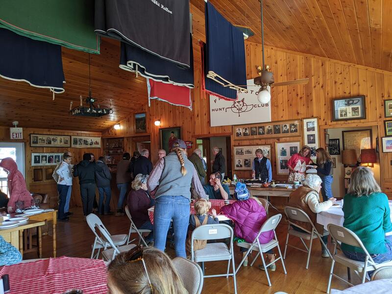 people at a gathering at the Farmington Hunt clubhouse, paneled walls with photos