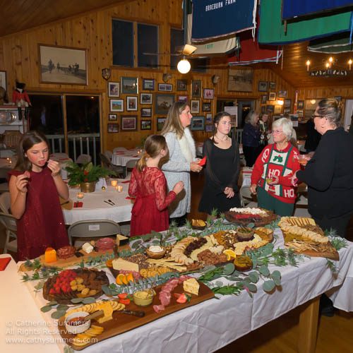 spread of food at holiday party in Farmington clubhouse with people around table