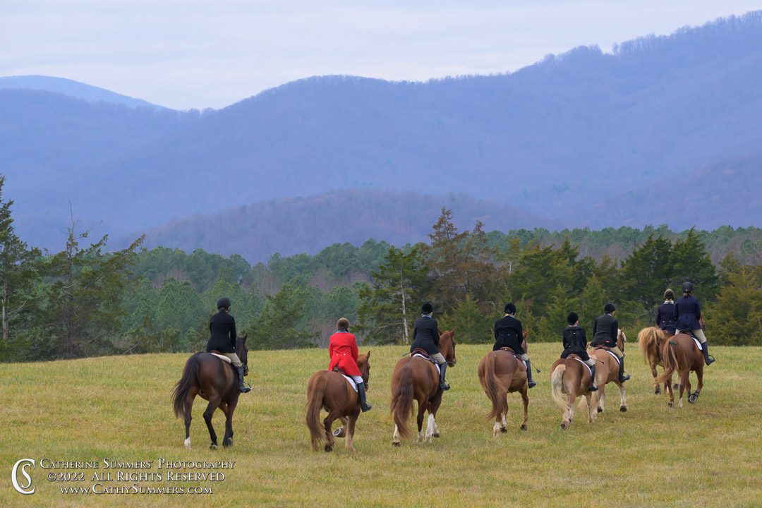 group of riders going across field toward mountain vistas