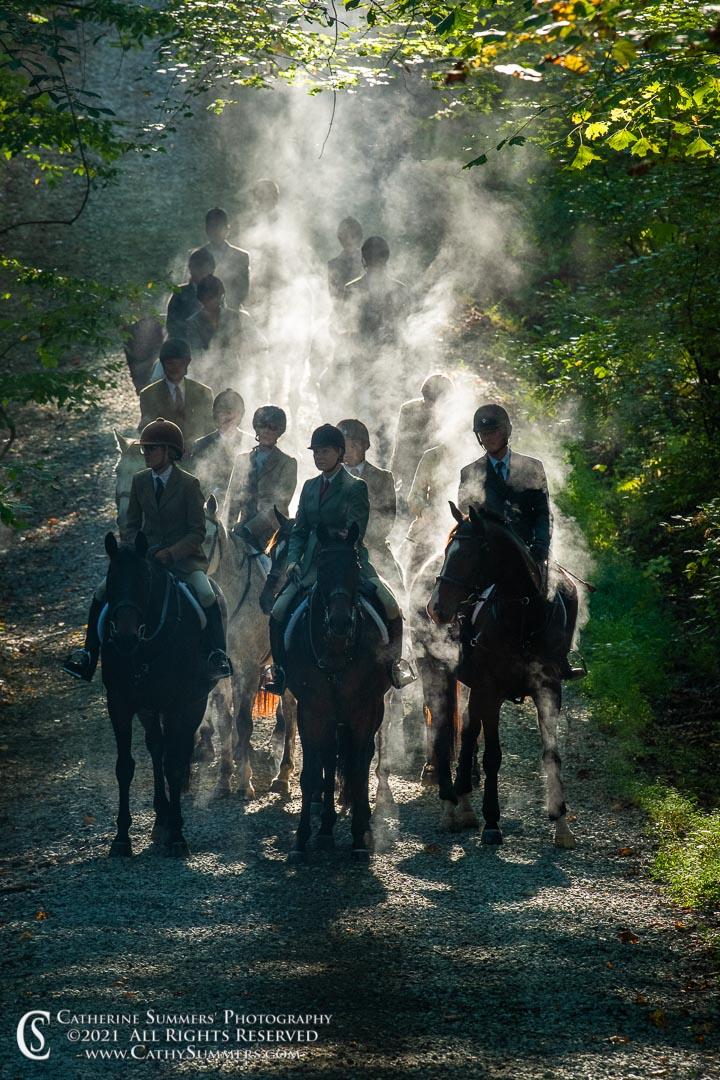 group of riders coming down a trail in steam coming off horses